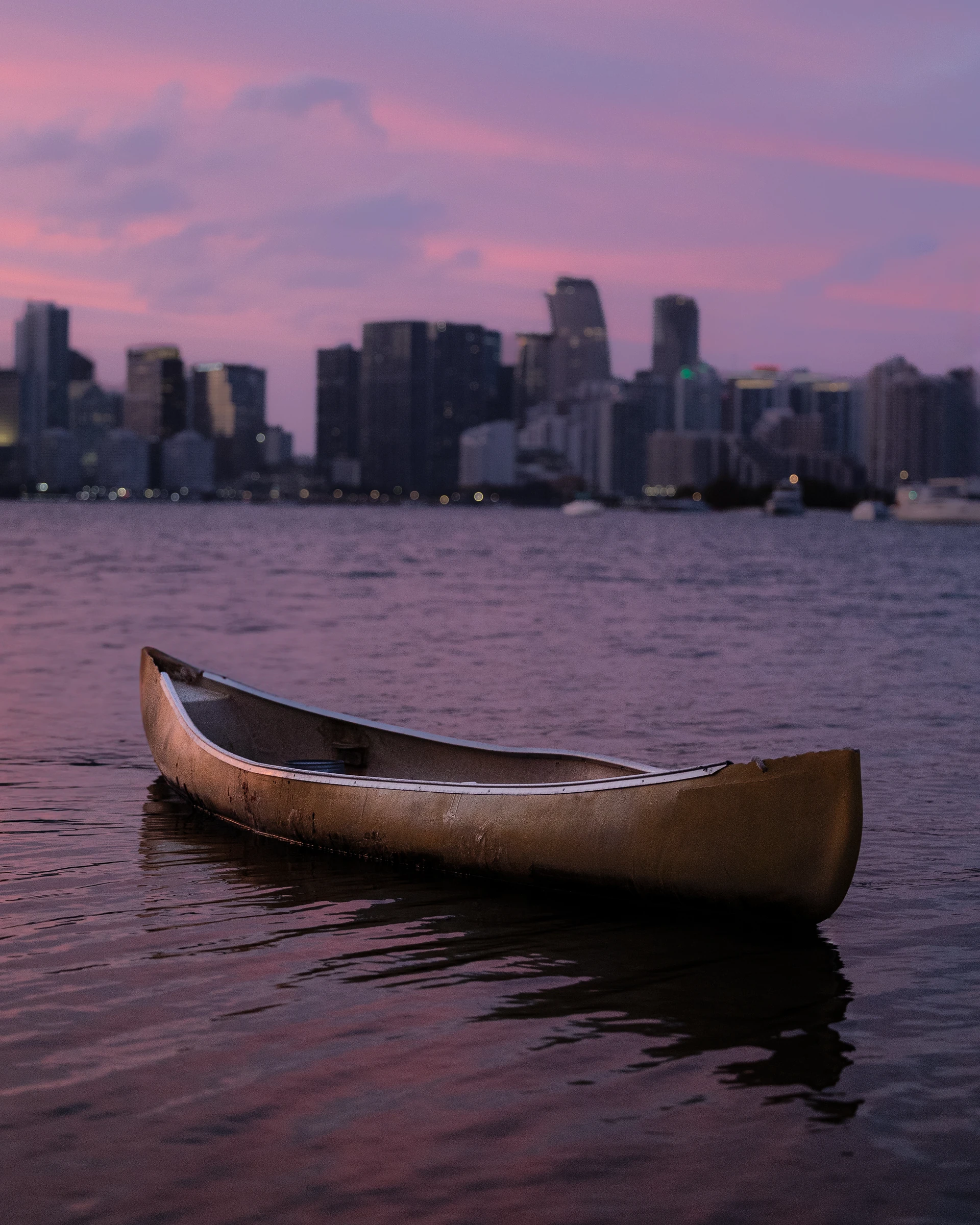 Canoe floating on calm water beneath a violet evening sky